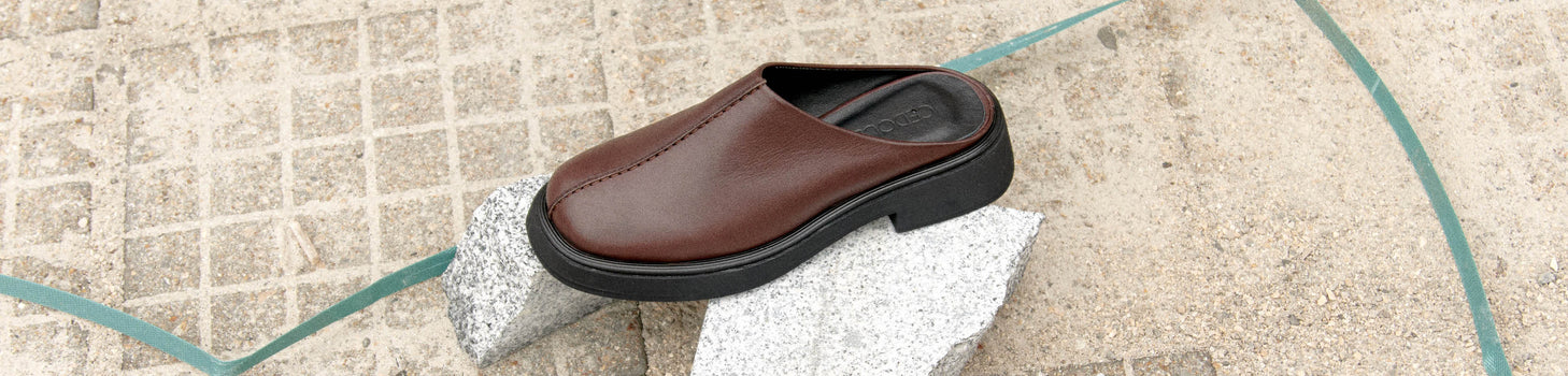 Legs of a woman sitting on a sofa wearing green chunky lug sole boots and velvet green wide leg pants with zebra print