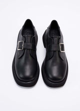 Lade das Bild in den Galerie-Viewer, Draufsicht eines Paares Unisex-Halbschuhe aus dem Hause Cedoublé. Die Schuhe sind aus Qualitätsleder in schwarz gefertigt. Dieses Leder ist mit dem Gold-Standard der Leather Working Group ausgezeichnet und weist neben angenehmen Trageeigenschaften auch einen feinen Glanz auf. Über dem Spann des Schuhs befindet sich ein Lederriemen mit einer eckigen, silberfarbenen Schnalle. Die Front der Schuhe ist eckig und leicht abgerundet. Es handelt sich um einen modischen Klassiker.