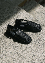 Lade das Bild in den Galerie-Viewer, Black leather unisex fisherman sandals with chunky outsole illuminated by the sun