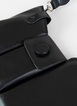 Lade das Bild in den Galerie-Viewer, Detailfoto einer schwarzen Crossbody-Bag aus weich gepolstertem Glattleder mit drei voneinander abgetrennten Fächern und einem farblich passenden, breiten Gurt aus Leder mit Karabinerhaken
