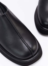 Lade das Bild in den Galerie-Viewer, Nahaufnahme der Schuhfront eines coolen Clog-Modells aus schwarzem, zertifiziertem Echtleder. Gut zu sehen ist das Design-Detail, eine raffinierte Wulstnaht, die den Schuhschaft optisch in zwei Seiten unterteilt. 
