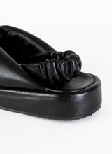 Load image into Gallery viewer, Detailbild einer Knotted Sandal in schwarz aus weich gepolstertem Leder mit einem gerafften Fersenriemen, ebenfalls aus weich gepolstertem, schwarzem Leder.

