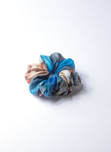 Load image into Gallery viewer, Scrunchie aus reiner, gebatikter Seide mit Farbverläufen von Naturtönen und Blau. Es handelt sich um einen zarten, leichten Seidenstoff. Das Volumen ist bauschig.
