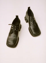 Load image into Gallery viewer, Analoges Foto von einem Paar extravaganter, schwarzer Lederschuhe mit Schnürung, Ösen und einem besonderen, klobigen Absatz. Die Schuhfront hat eine Karreeform.
